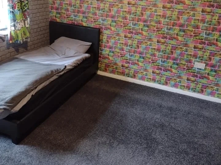 Grey bedroom carpet against a graffiti-mural feature wall — carpet fitters covering Cullercoats