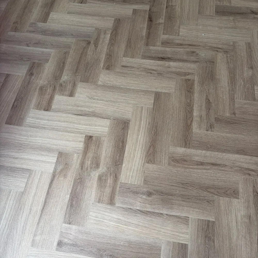 Oak-effect herringbone LVT close-up — plank quality affects price